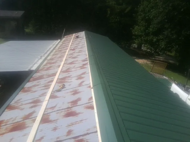 Old rusted panels beside newly installed green metal roofing — Wind Damage Roof Repair by Roofing Brothers in Lincoln University