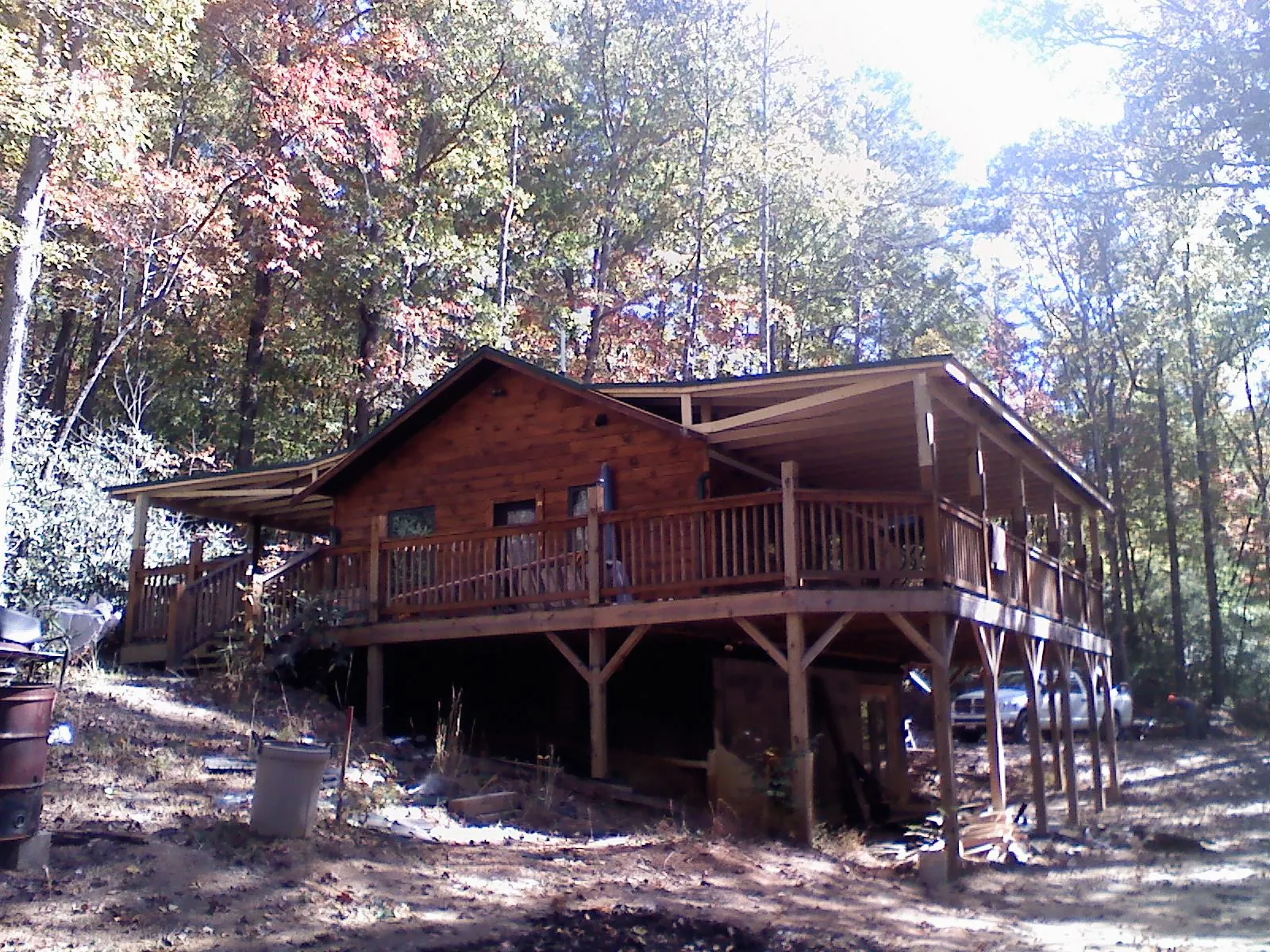 Log cabin with a wraparound porch and metal roof in the fall in Lincoln University