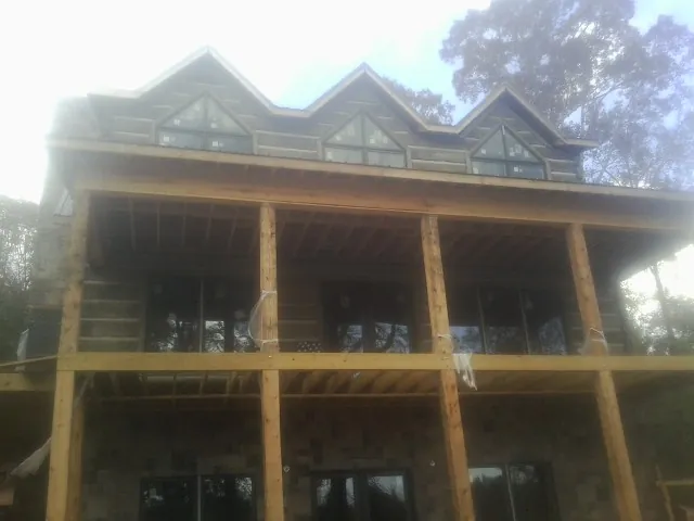 Dormers and porch framing on a large log home under construction — Roof Coating work by our crew in Lincoln University