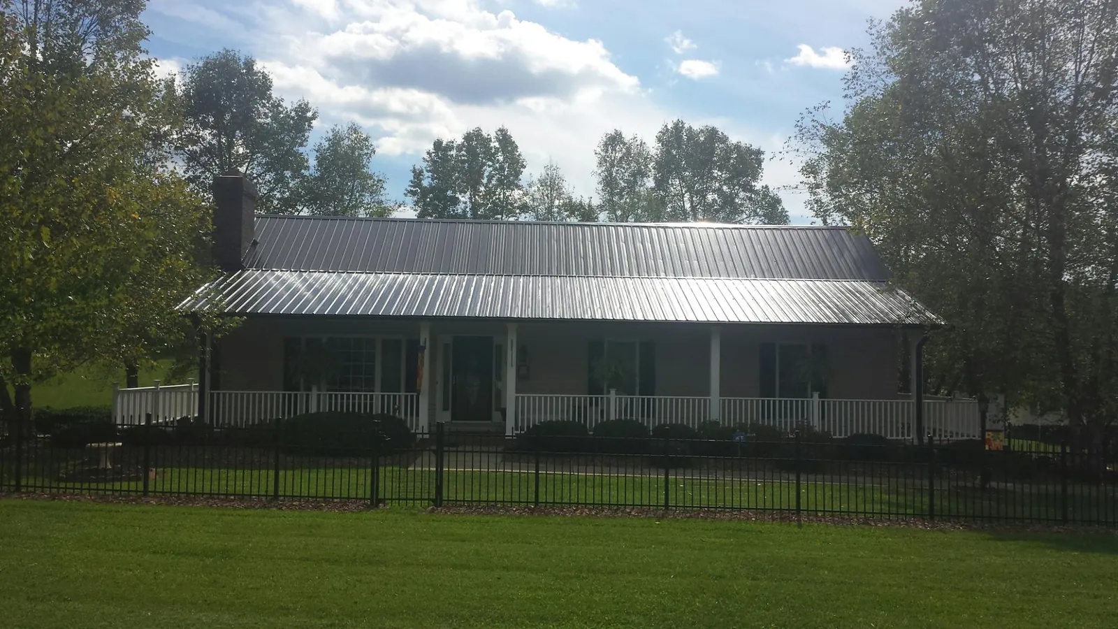 Gray metal roof on a brick ranch with a full width front porch — Gutter Guard Installation work by our crew in Lincoln University