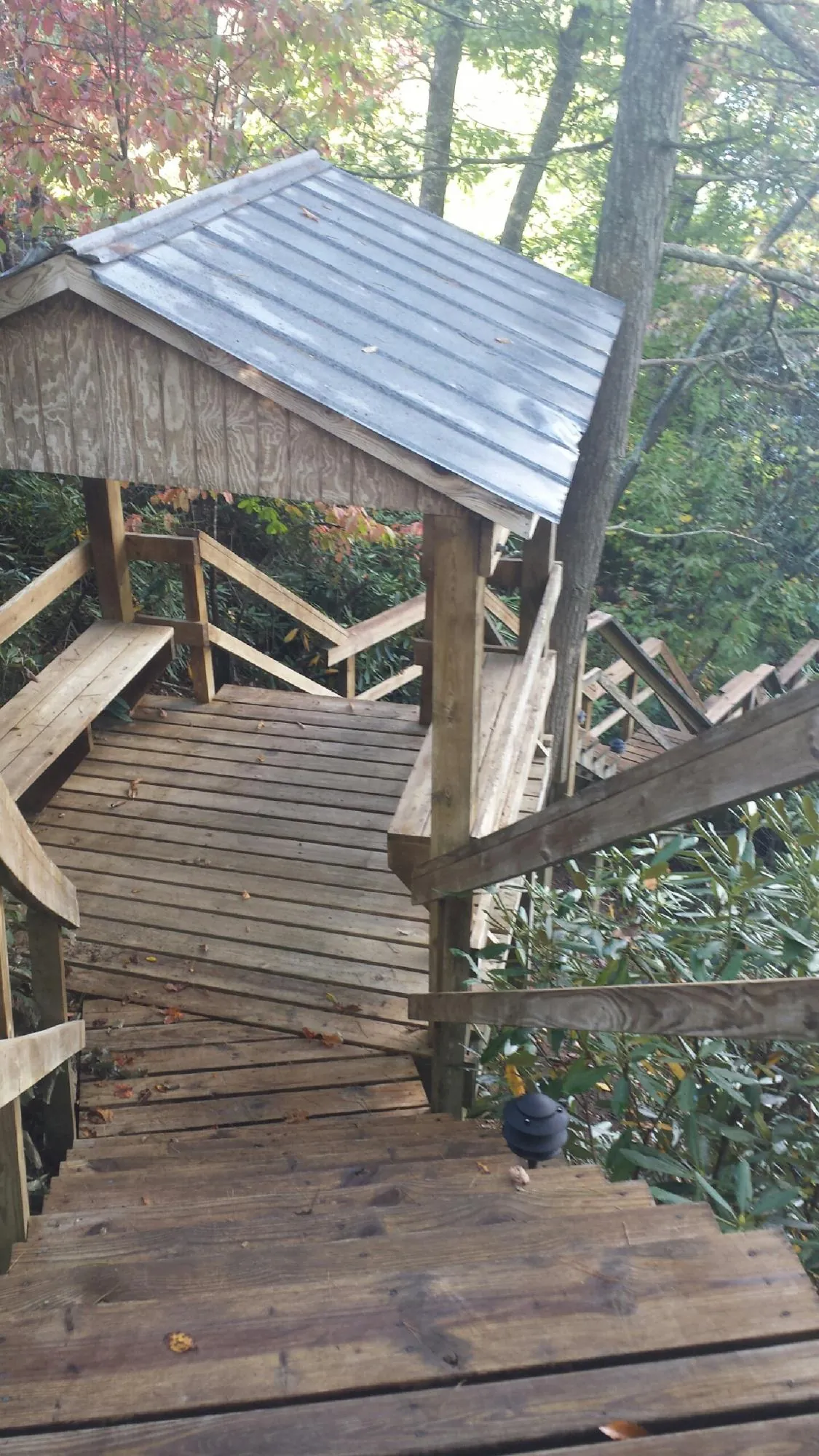 Metal roofed shelter over wooden steps on a wooded walkway — Skylight Repair & Installation work by our crew in Lincoln University