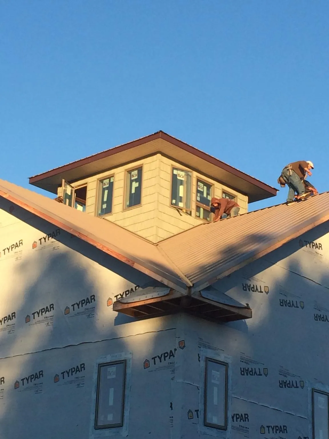 Roofers working around a rooftop cupola on a new metal roof at sunset — Roof Waterproofing in Lincoln University by Roofing Brothers